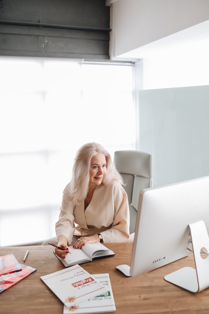 Businesswoman reviewing documents at a stylish desk in a well-lit office environment.